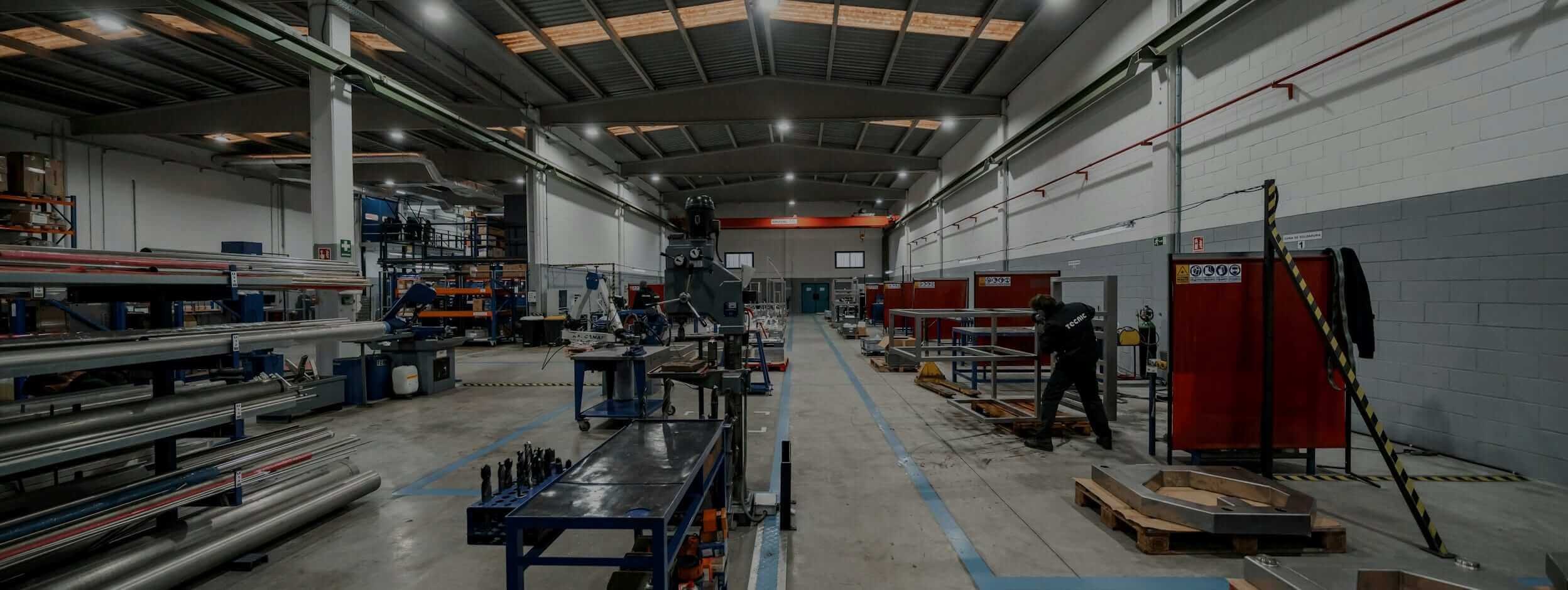 Atelier de tôlerie : racks de barres, perceuse, cabines de soudage et opérateur reliés à ISI®